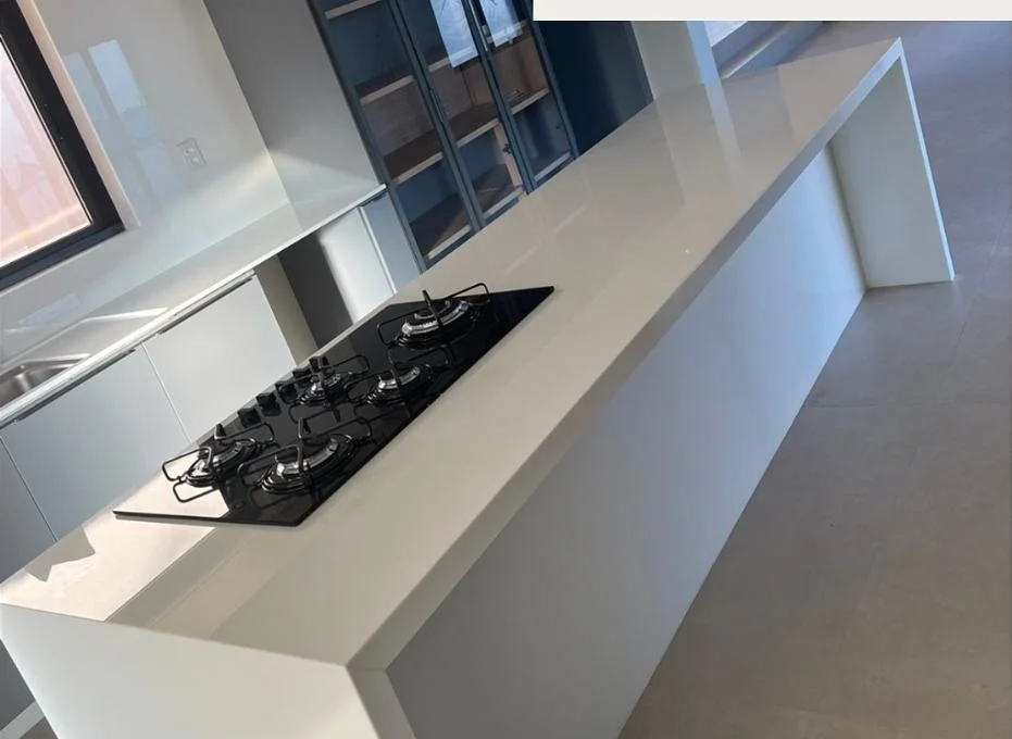 Ilha de cozinha com bancada branca e cooktop, executada pela Nova Stone